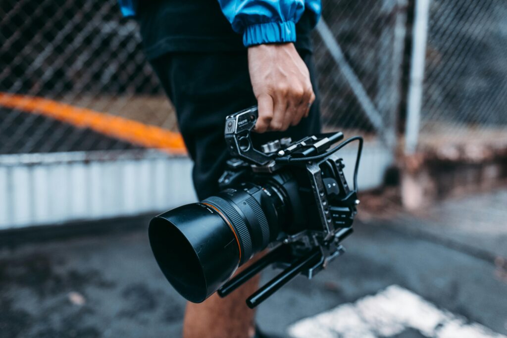 pexels-photo-3101497-3101497 Focused image of a person holding a professional film camera outdoors.